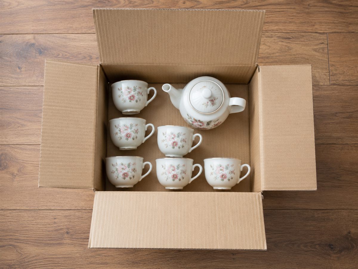 An open cardboard box with a porcelain tea set, photographed for AI recognition